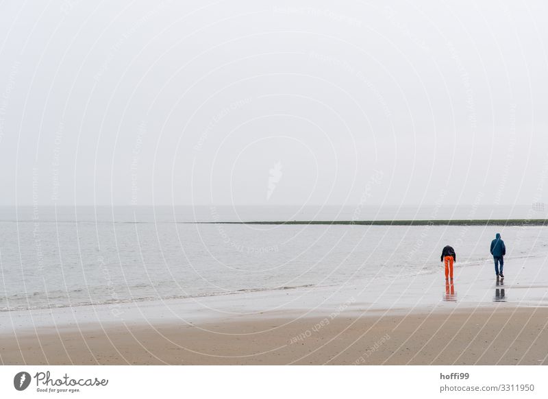 zwei Menschen am Strand von Baltrum bei Regen und Sturm Ausflug Paar Partner 2 18-30 Jahre Jugendliche Erwachsene Landschaft Sand Wasser Himmel Wolken Wetter