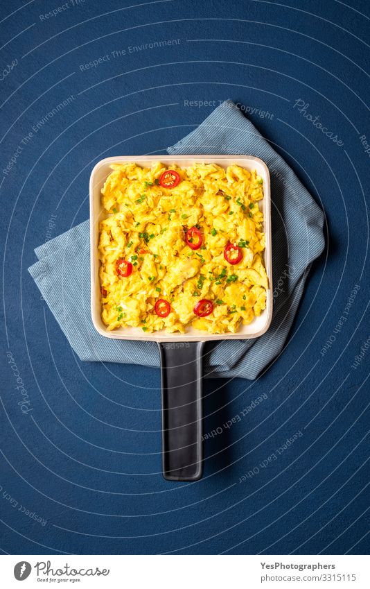 Rührei-Pfanne in Nahaufnahme auf blauem Tisch. Lebensmittel Frühstück Mittagessen Gesunde Ernährung Küche frisch gelb Tradition obere Ansicht Blauer Hintergrund