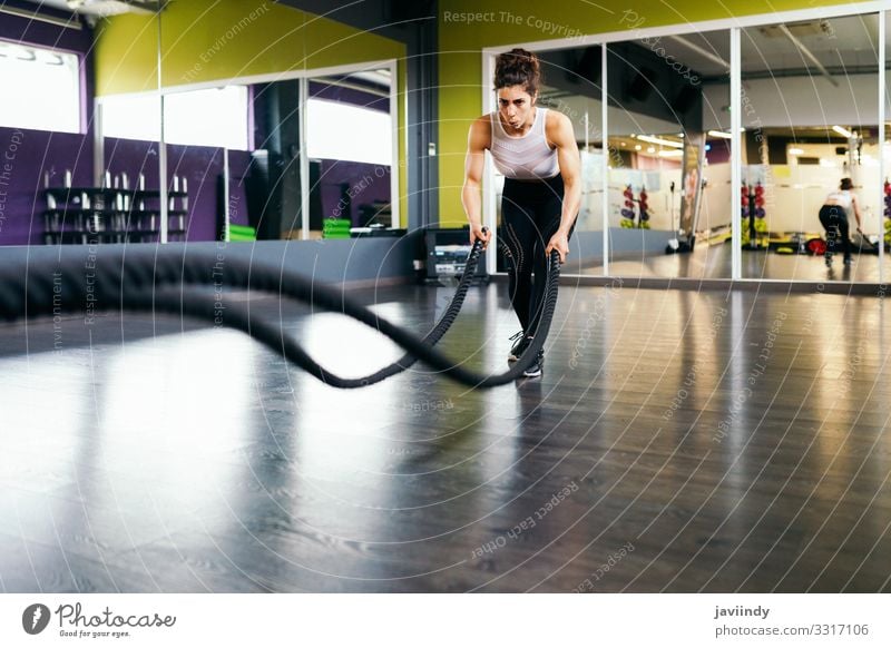 Junge und sportliche Frau, die Trainingsseile in einer Turnhalle benutzt. Lifestyle Körperpflege Wellness Club Disco Sport Seil Mensch feminin Erwachsene