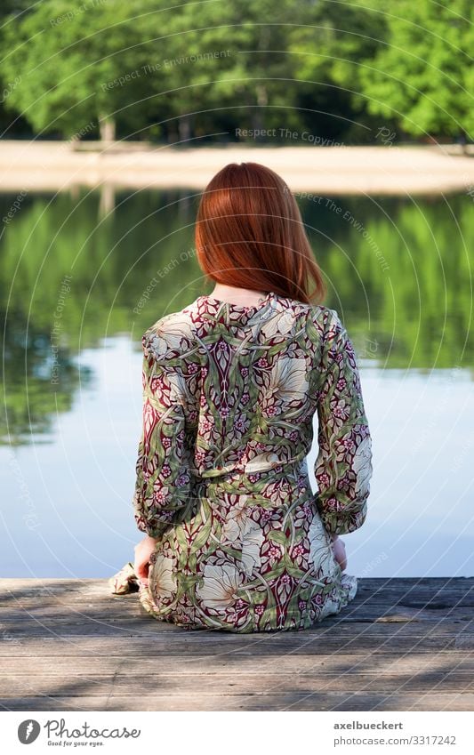 Junge Frau sitzt auf einem Holzsteg und schaut auf den See Lifestyle elegant Erholung Freizeit & Hobby Ferien & Urlaub & Reisen Sommer Strand Mensch feminin