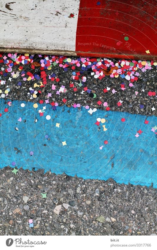 Buntes Konfetti liegt am schmutzigen Donnerstag, während Fasching; Karneval auf der Straße am Boden, zwischen Markierungen als Warnungen, bei einem Karnevalumzug,  und verschmutzt die Umwelt