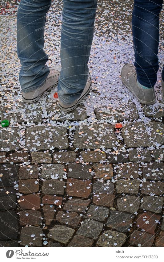 Drei Beine ins Jeans und Turnschuhen, stehen auf der Straße in Konfetti, an Fasching / Karneval. Füße jeans konfettiregen Feier Feiern Fasnet Feste & Feiern