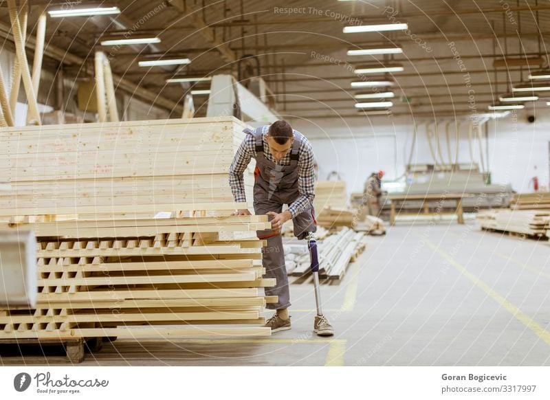 Behinderter junger Mann mit Beinprothese in der Möbelfabrik Arbeit & Erwerbstätigkeit Beruf Handwerker Arbeitsplatz Fabrik Industrie Business Werkzeug