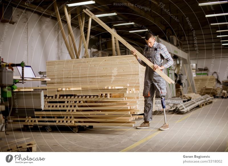 Behinderter junger Mann mit einer Beinprothese in der Möbelfabrik Arbeit & Erwerbstätigkeit Beruf Arbeitsplatz Fabrik Industrie Business Werkzeug Erwachsene