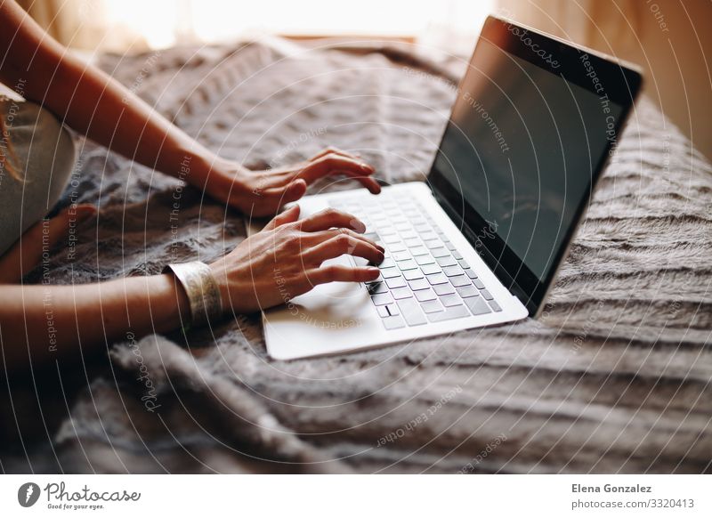 Die Hände der Frau beim Tippen auf der Laptop-Tastatur im gemütlichen Schlafzimmer. Lifestyle Studium Arbeit & Erwerbstätigkeit Beruf Arbeitsplatz Büro