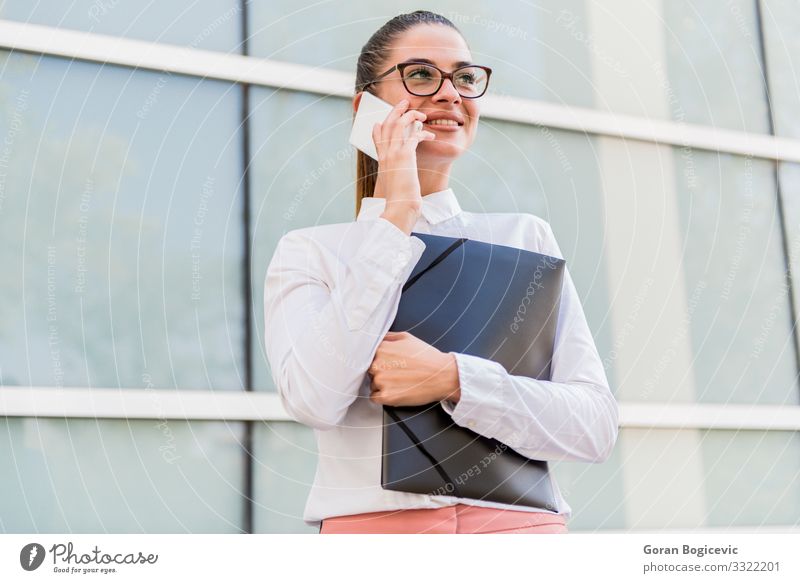 Junge Geschäftsfrau, die ein Smartphone benutzt und Dokumente aufbewahrt Kapitalwirtschaft Business Karriere sprechen PDA Technik & Technologie Mensch