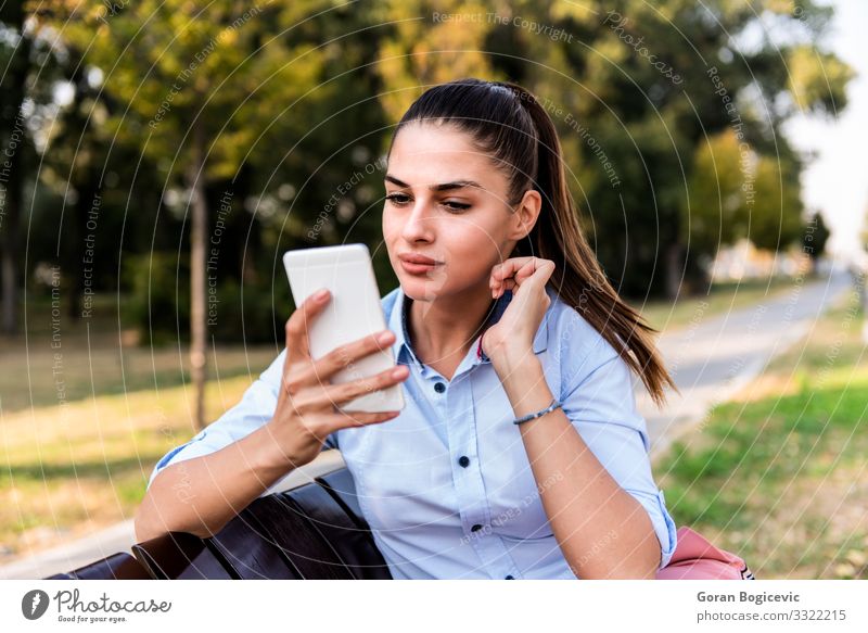 Hübsches junges Mädchen auf einer Bank sitzend mit Mobiltelefon Lifestyle Glück schön Sommer Sonne Telefon PDA Technik & Technologie Mensch Junge Frau