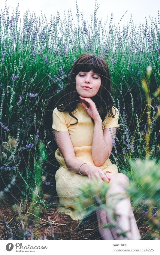 Junge brünette Frau sitzt umgeben von Lavendel jung hübsch retro altehrwürdig Natur natürlich wirklich offen sich[Akk] entspannen Ruhe Szene Blumen Frühling