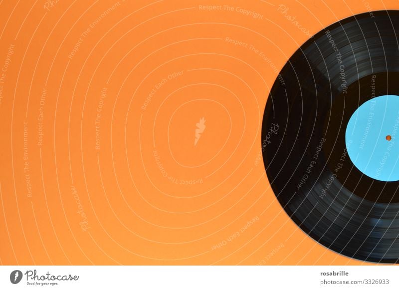 alte Schallplatte aus Vinyl auf orangenem Untergrund mit Freiraum links macht auch ein schönes | Geräusch Schallplatten. LP antik vintage Musik Disco schwarz