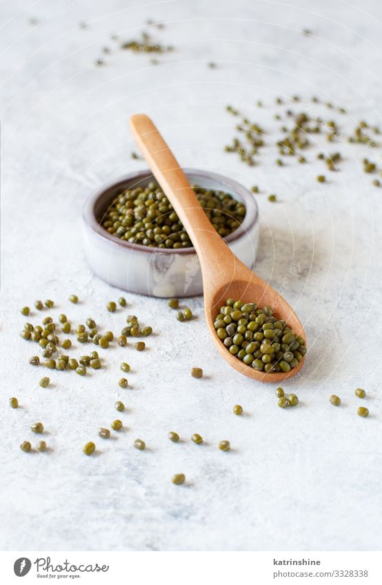 Getrocknete Mungobohnen in einer Schüssel mit einem Holzlöffel Vegetarische Ernährung Diät Schalen & Schüsseln Löffel Tisch grün weiß Mungbohnen Bohnen mung