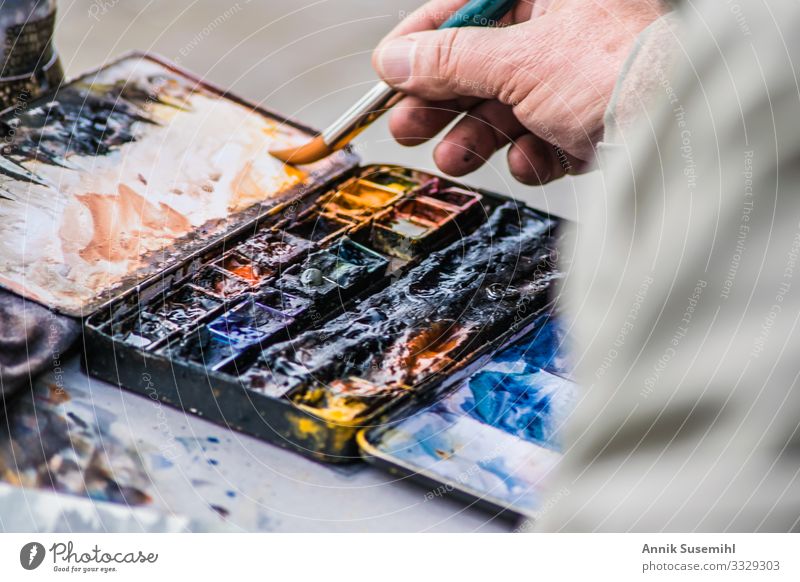 Hand eines Malers vor Palette mit Ölfarben Mensch maskulin Finger Kunst Künstler Arbeit & Erwerbstätigkeit zeichnen ästhetisch blau braun mehrfarbig gelb gold