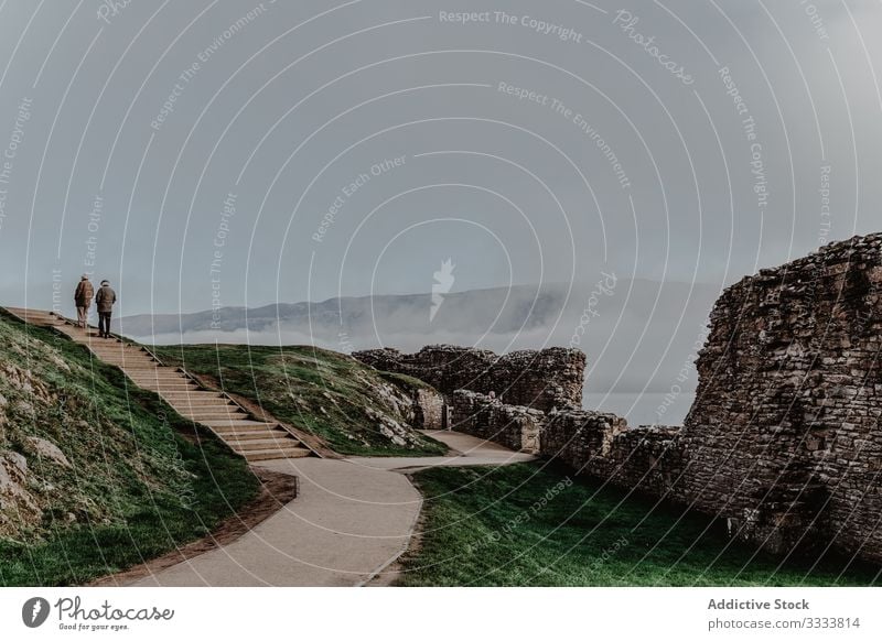 Touristen gehen auf Steintreppe eines verfallenen Gebäudes Menschen Burg oder Schloss Berge u. Gebirge Nebel Hügel Felsen Ansicht schlendern Landschaft Treppe