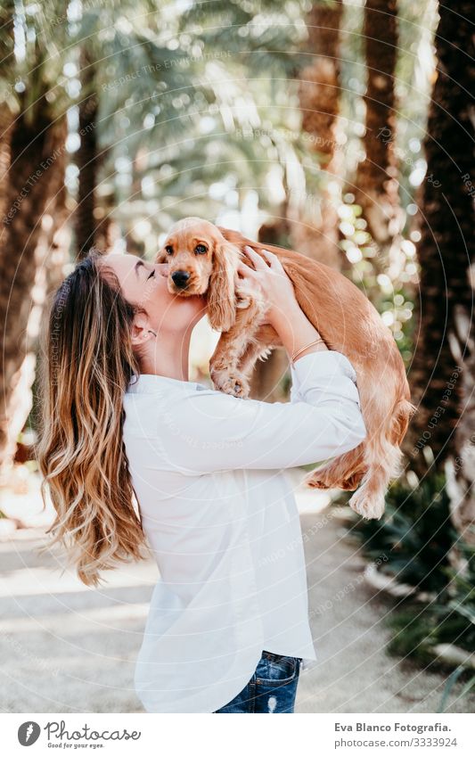 junge Frau und ihr süßer Cockerspaniel-Welpe im Freien in einem Park Hund Haustier Sonnenstrahlen Außenaufnahme Liebe Umarmen Lächeln Rückansicht Küssen züchten