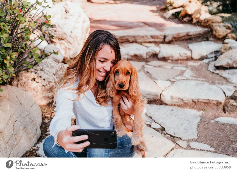 junge Frau, die mit ihrem süßen Cockerspaniel-Welpen einen Selfie mit nach draußen nimmt Handy Technik & Technologie Cocker Spaniel Hund Haustier Park