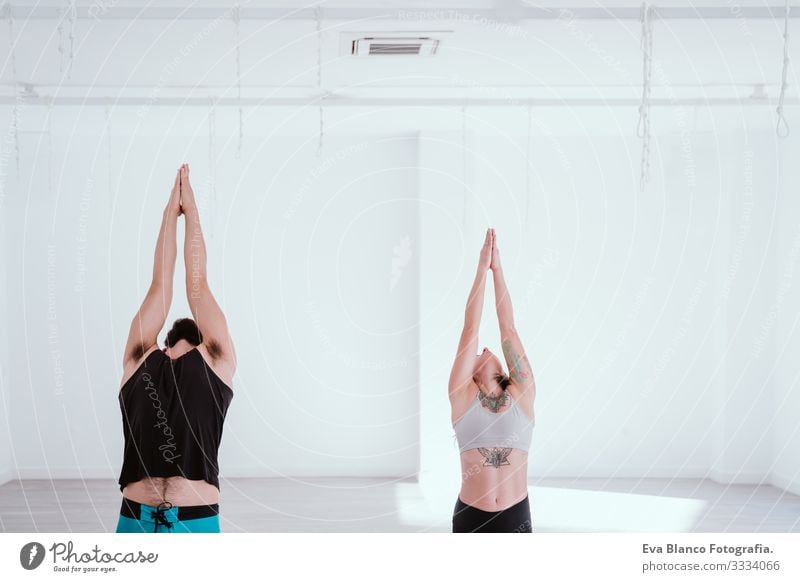 junger Mann und Frau, die in der Sporthalle Yoga-Sport betreiben. Gesunder Lebensstil Junge Gesundheit Lifestyle Innenaufnahme Studioaufnahme weiß hispanisch