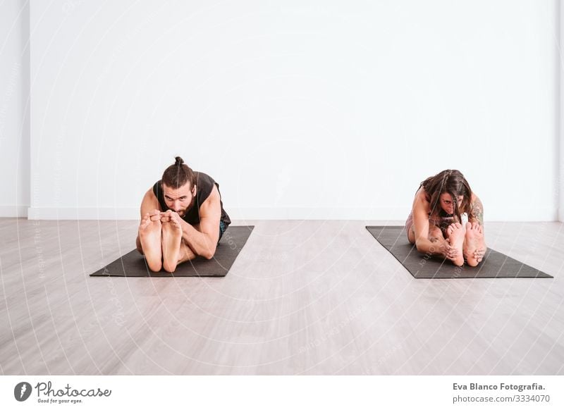 junger Mann und Frau, die in der Sporthalle Yoga-Sport betreiben. Gesunder Lebensstil Junge Gesundheit Lifestyle Innenaufnahme Studioaufnahme weiß hispanisch