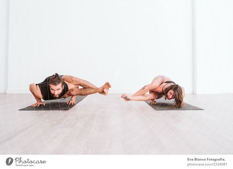 junger Mann und Frau, die in der Turnhalle Yoga-Sport betreiben. Gesunder Lebensstil Junge Gesundheit Lifestyle Innenaufnahme Sporthalle Studioaufnahme weiß