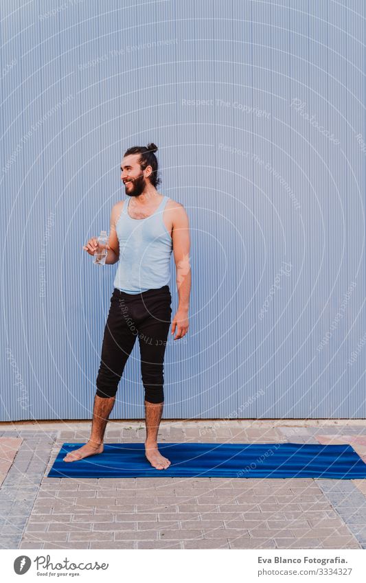 mann in der stadt, der yoga-sport betreibt und wasser trinkt. blauer hintergrund. gesunde lebensweise Yoga Mann Sport Gesundheit Außenaufnahme Großstadt