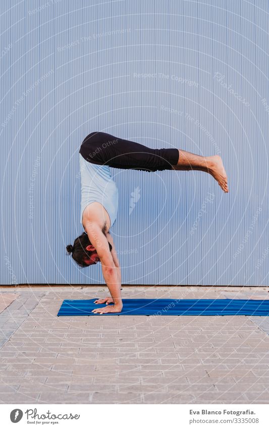 mann in der stadt, der yoga-sport betreibt. blauer hintergrund. gesunde lebensweise Yoga Mann Sport Gesundheit Außenaufnahme Großstadt Blauer Hintergrund