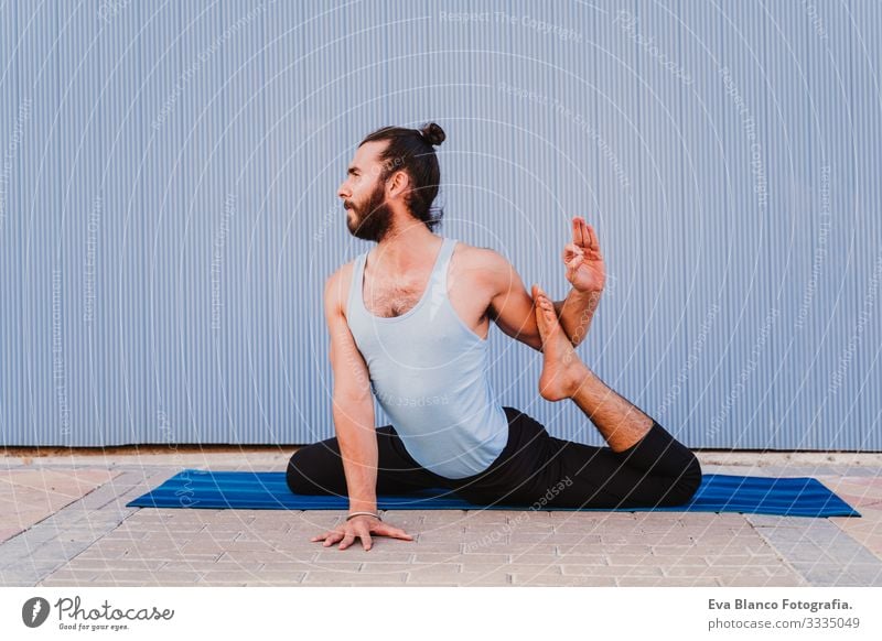 mann in der stadt, der yoga-sport betreibt. blauer hintergrund. gesunde lebensweise Yoga Mann Sport Gesundheit Außenaufnahme Großstadt Blauer Hintergrund