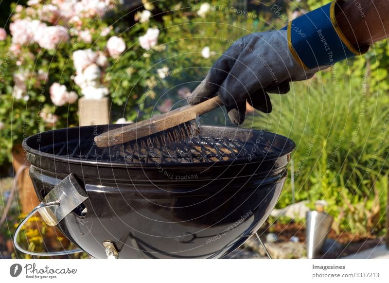 Grill reinigen. Männliche Hand mit Handschuhen säubert runden Grill mit Bürste. Vorbereitung eines Grills vor dem Kochen. Mann putzt einen Grill im Garten