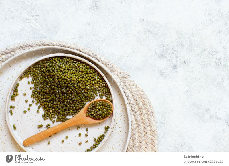 Getrocknete Mungbohnen mit einem Löffel auf einem weißen Tisch Vegetarische Ernährung Diät Teller oben grün Bohnen mung getrocknet Sehne Lebensmittel Gesundheit