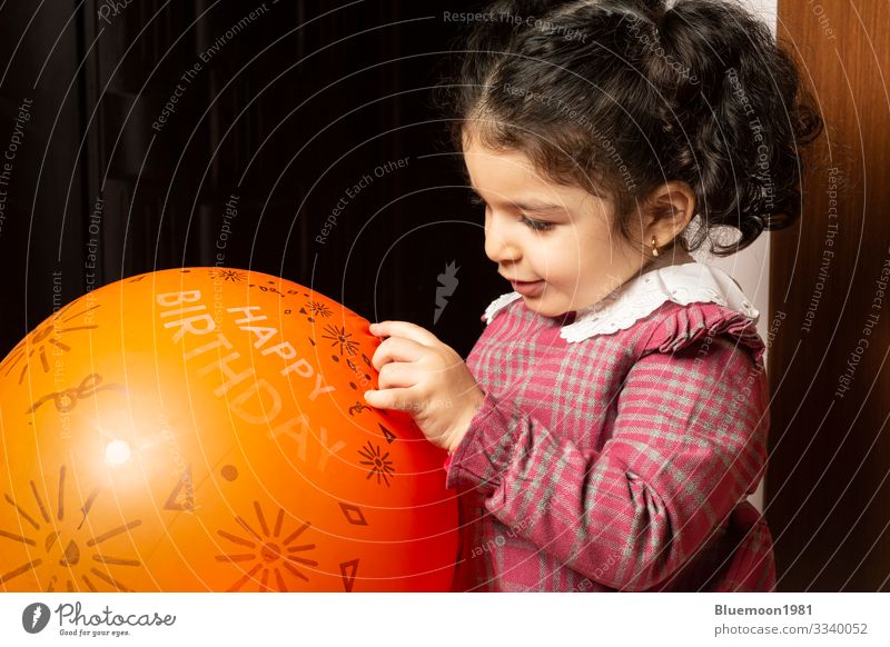 Ein kleines Mädchen spielt mit einem orangenen Geburtstagsballon Lifestyle Design Freude Gesicht Spielen Feste & Feiern Kind Industrie Mensch Kindheit 1