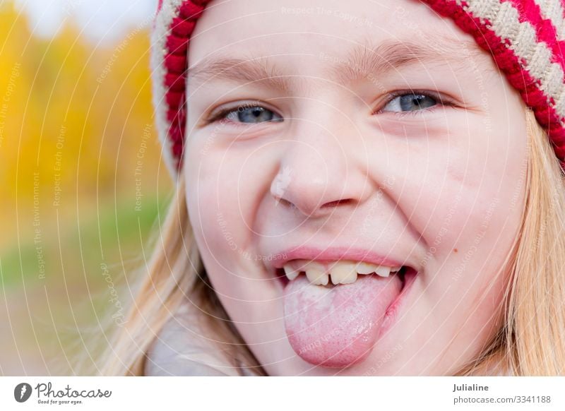 Süßes Mädchen streckt die Zunge heraus Kind Schulkind Frau Erwachsene Kindheit Herbst blond Lächeln lang niedlich blau weiß Gefühle ausmachen Vorschulkind eine