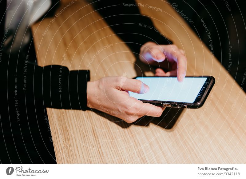 Nahaufnahme einer jungen Frau, die in einem Café oder Restaurant in einem Innenraum ein Mobiltelefon benutzt. Unkenntnis der Lebensweise von Personen Handy