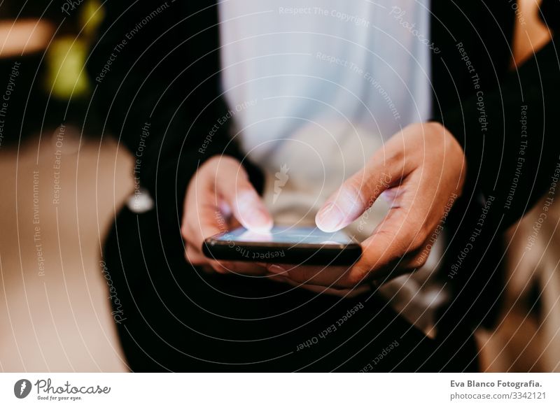 Nahaufnahme einer jungen Frau, die in einem Café oder Restaurant in einem Innenraum ein Mobiltelefon benutzt. Unkenntnis der Lebensweise von Personen Handy