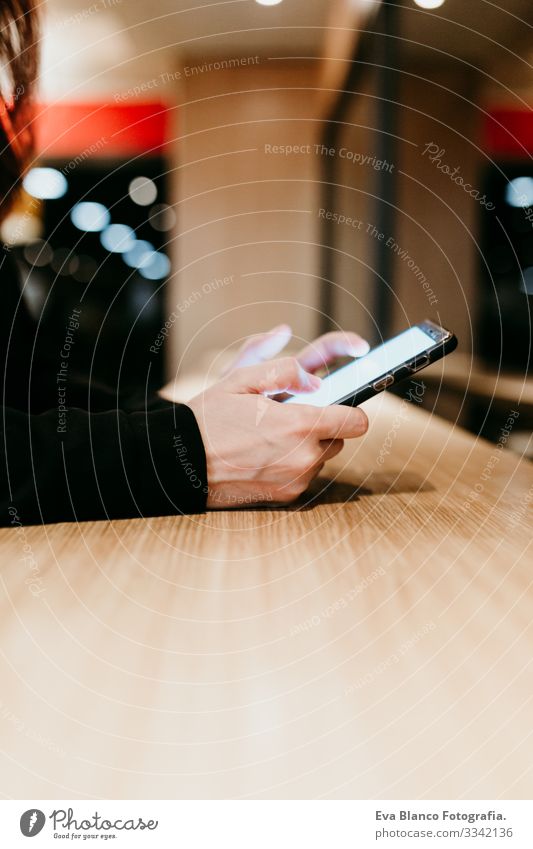 Nahaufnahme einer jungen Frau, die in einem Café oder Restaurant in einem Innenraum ein Mobiltelefon benutzt. Unkenntnis der Lebensweise von Personen Handy