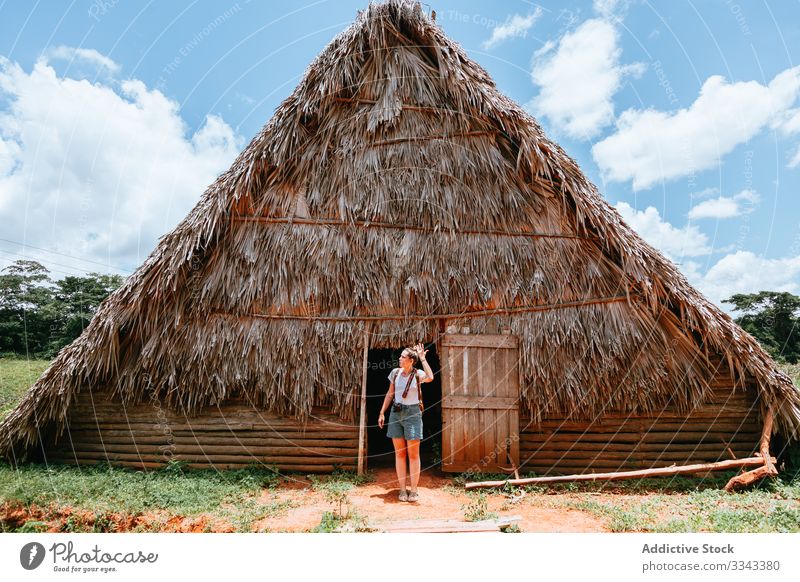 Frau im Urlaub in der Nähe eines alten Hauses auf dem Land Landschaft ländlich Türöffnung Stehen strohgedeckt Dach Blauer Himmel Sommer Cloud grün Gras reisen