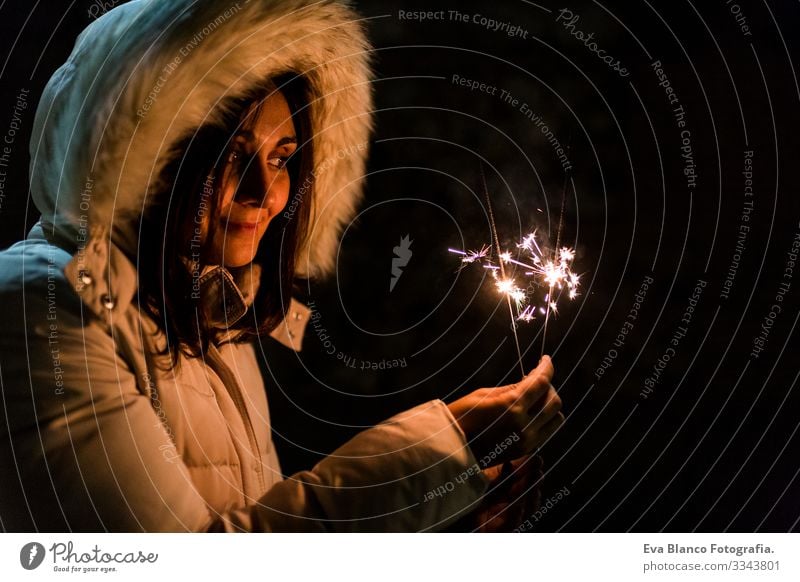 eine schöne junge Frau, die nachts funkelt, Spaß hat und lächelt Party Nacht Licht Freude dunkel Feuer Feuerwerk Hand Flamme Funkelt hell Lifestyle