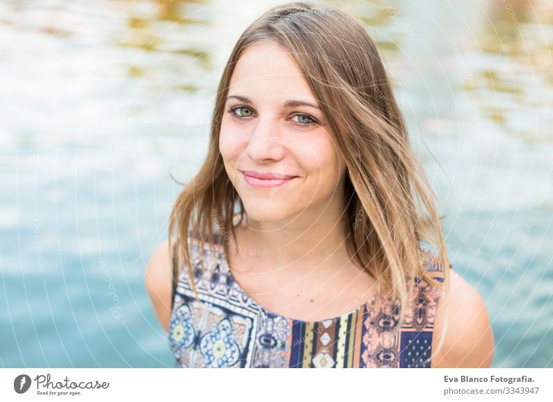 Porträt einer schönen jungen Frau im Freien, die in die Kamera schaut und lächelt. blauer Wasserhintergrund Jugendliche Glück Mädchen Lifestyle Beautyfotografie