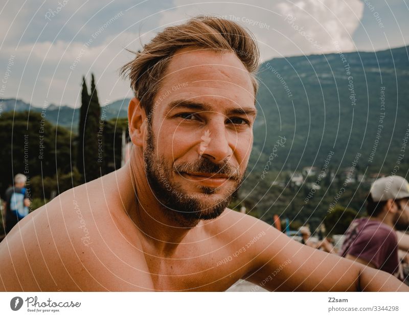 Mann chillt am Strand von Torbole gardasee torbole strand erholung zufrieden glücklich freiheit freizeit urlaub berge portrait bart jung sunnyboy blond hübsch