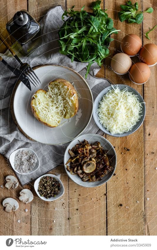 Tisch mit Zutaten und offener gefüllter Kartoffel Lebensmittel Essen zubereiten hölzern Kraut Käse Gewürz Erdöl frisch Gemüse Diät Speise Gabel rustikal