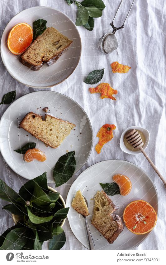 Geschnittener Kuchen und Zitrusfrüchte auf Tellern auf dem Tisch Mandarine Frucht Dessert aufgeschnitten Portion Essen orange süß Gebäck Feinschmecker lecker