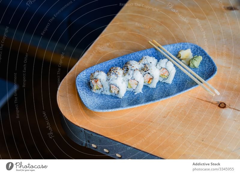 Frisches Sushi mit Stäbchen auf dem Tisch Asiatische Küche Speise Essstäbchen Reis hölzern Ingwer Wasabi Sesam Abendessen traditionell Meeresfrüchte Teller