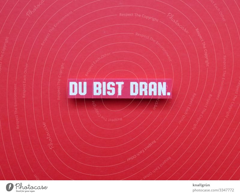 DU BIST DRAN. Schriftzeichen Schilder & Markierungen Kommunizieren rot weiß Neugier Beginn Erwartung Farbfoto Studioaufnahme Menschenleer Textfreiraum links