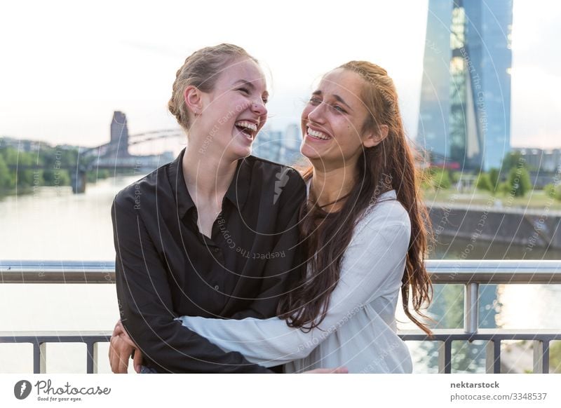 Freundinnen umarmend und lachend auf der City Bridge Freude Glück Frau Erwachsene Freundschaft Jugendliche Jugendkultur Natur Fluss Hochhaus Brücke Gebäude