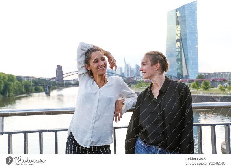 Freundinnen lächeln auf der Stadtbrücke über den Fluss Glück Frau Erwachsene Freundschaft Jugendliche Jugendkultur Natur Hochhaus Brücke Gebäude Lächeln Mädchen