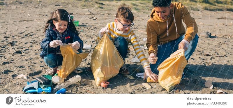 Junge Freiwillige, die am Strand Müll aufsammeln Glück Camping Kind Internet Mensch Frau Erwachsene Mann Menschengruppe Umwelt Sand Kunststoff Lächeln dreckig