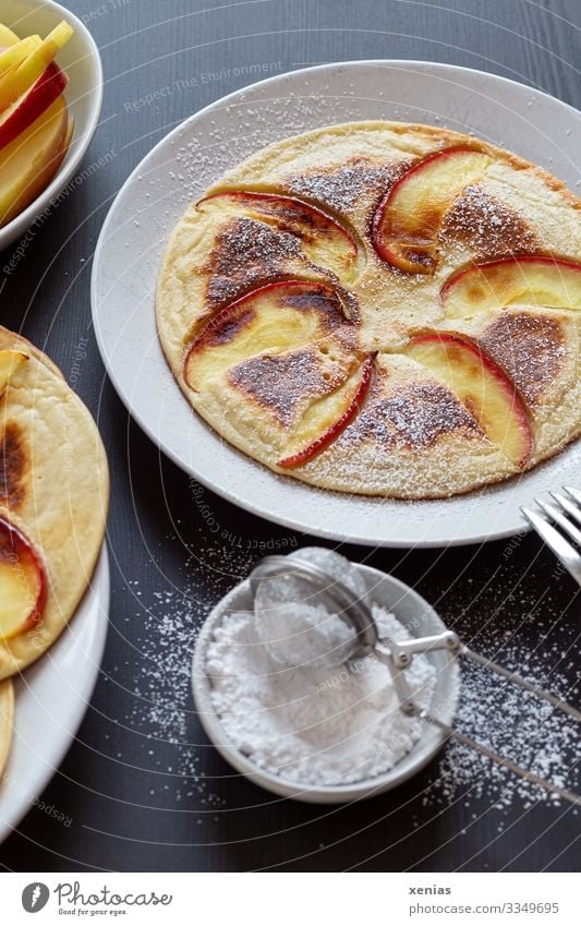 Pfannkuchen mit Apfel und Puderzucker auf weißem Teller Teigwaren Backwaren Süßwaren Apfelspalte Zucker Ernährung Bioprodukte Lebensmittel