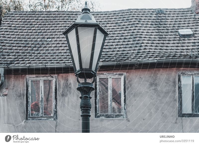 Straßenlaterne vor einem alten Haus Dorf Menschenleer Gebäude Mauer Wand Fassade Fenster Dach Armut hässlich retro braun grau schwarz Senior Verfall