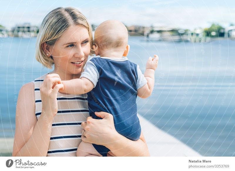 Mutter hält einen kleinen Sohn mit einer Meeresbucht im Hintergrund Freude Glück schön Gesicht Leben Sommer Strand Kindererziehung Baby Kleinkind Frau