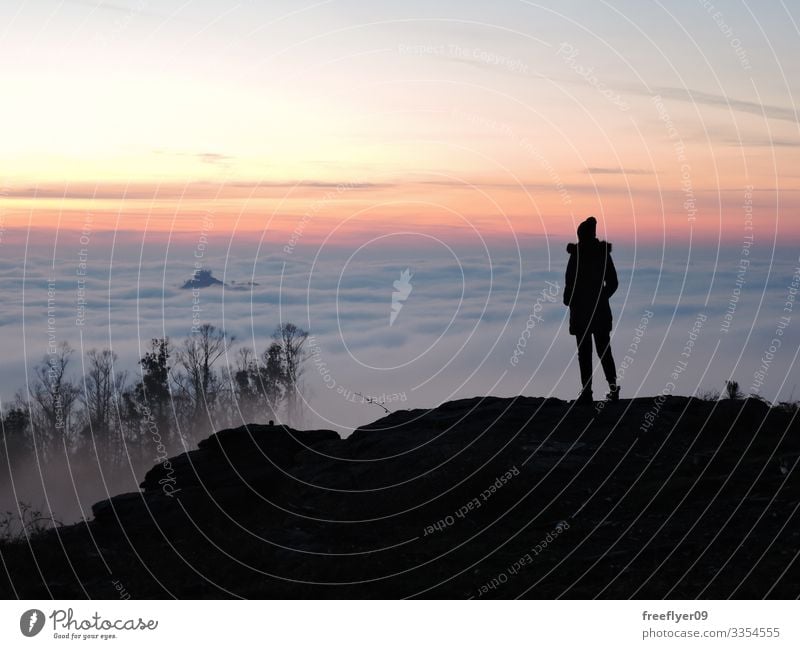 Einsame Wanderin, die vom Gipfel eines Berges aus die Wolken betrachtet einsam allein Frau Wanderer Beanie Hut oben wandern Tourist Tourismus Landschaft Höhe