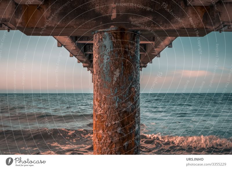 rostige Seebrücke von unten Himmel Sommer Schönes Wetter Wellen Ostsee Meer Rost Unendlichkeit maritim blau braun rosa ruhig Fernweh Symmetrie Brücke symetrisch