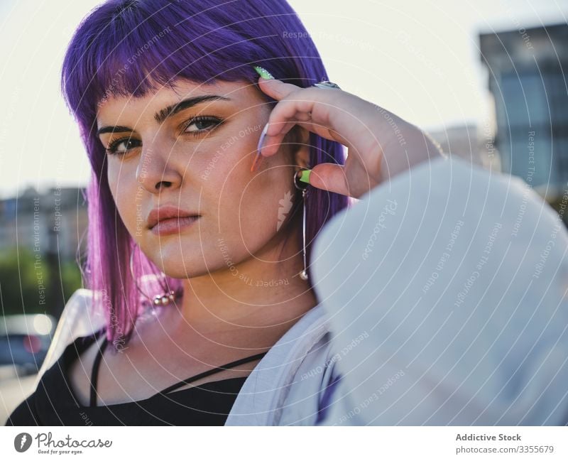 Frau mit violettem Haar lehnt an Metallzaun Lehnen berührend stylisch urban purpur Frisur Jacke glänzend Zaun Revier selbstbewusst Mode jung Stil Model Straße