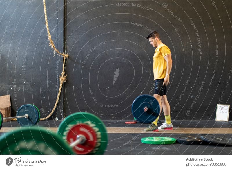 Muskulöser Mann hebt Langhantel im modernen Fitnessstudio Sportler Training Gewichtheben Curl-Hantel schwer anstrengen Erwachsener stark männlich angespannt