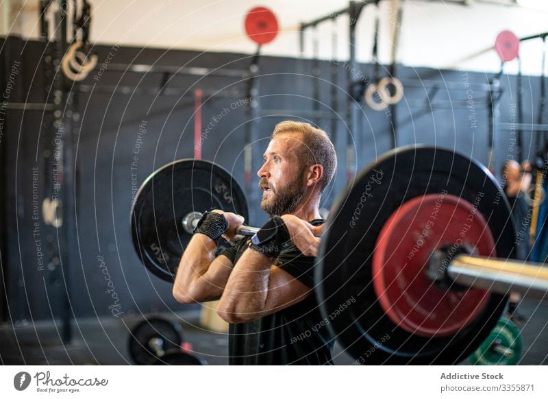 Muskulöser Mann hebt Langhantel im modernen Fitnessstudio Sportler Training Gewichtheben Curl-Hantel schwer anstrengen Erwachsener stark männlich angespannt